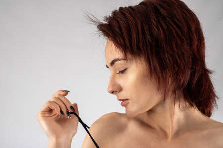 Studio photo of an attractive woman in a studio with a white background wearing red lingerie pulling her bra strap down from her shoulder seductively.の写真素材