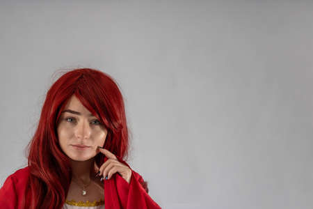 Full length young female attractive model in a studio with a white background, the model is wearing a red medieval costume with red auburn hairの写真素材