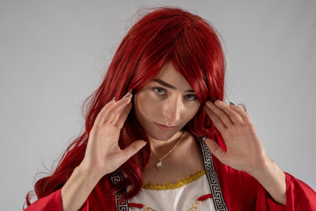 Full length young female attractive model in a studio with a white background, the model is wearing a red medieval costume with red auburn hairの写真素材