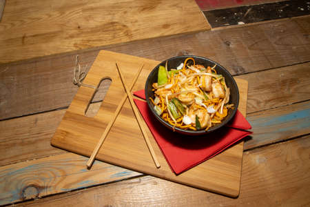 A delicious Chilli Bean King Prawn Noodles with chop sticks along side the bowl on a wooden chopping boardの写真素材