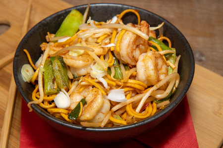 A delicious Chilli Bean King Prawn Noodles with chop sticks along side the bowl on a wooden chopping boardの写真素材