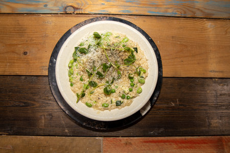 Top down view of a delicious meal of courgette, broad bean and pea risotto, on a wooden kitchen tableの写真素材