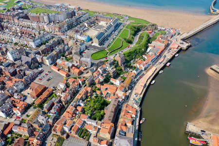 Aerial photo of the beautiful town of Whitby in the UK, North Yorkshire in the UK showing a top down view of the village by the harbour and sandy beach on a hot sunny summers dayのeditorial素材