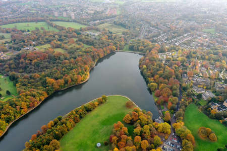 Aerial photo in autumn showing the beautiful autumn fall colours of a park in Leeds known as Roundhay Park in West Yorkshire UK, showing a typical British park and woods along side a lake.のeditorial素材