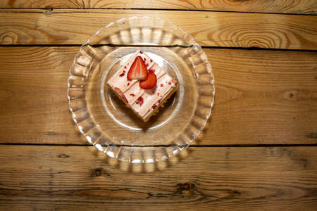 A delicious strawberry cake tray topped with fresh strawberries on a glass plate on a wooden table