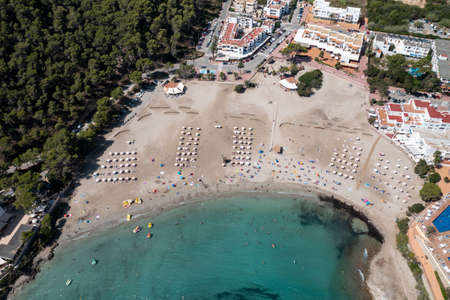 Top down aerial photo of the Spanish island of Ibiza showing the beautiful beach front and hotels on and the beach at Cala Llonga in the summer time in the Balearic Islands, Spainのeditorial素材