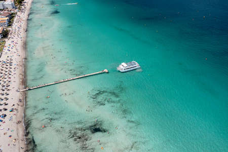 Aerial drone photo of the beach front on the Spanish island Majorca Mallorca, Spain showing a boat...