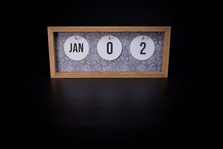 A wooden calendar block showing the date January 2nd on a dark black background 2nd day of the year conceptの写真素材