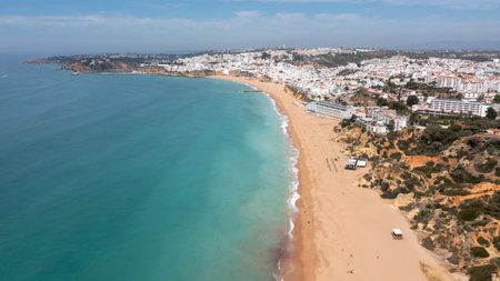 Aerial photo of the beautiful town in Albufeira in Portugal showing the Praia de Albufeira golden sandy beach, with hotels and apartments in the town, taken on a summers day in the summer time.の写真素材