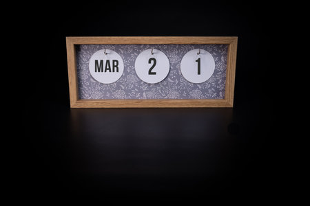 A wooden calendar block showing the date March 21st on a dark black background, save the date or date of an event concept.の写真素材