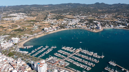 Aerial drone photo of a beach in the town of Sant Antoni de Portmany on the island of Ibiza in the Balearic Islands Spain showing the boating harbour and the beach known as Playa de San Antonioの写真素材