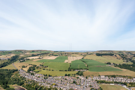 Aerial photo of the historic Yorkshire town of Huddersfield in the UK, showing the residential housing estates with green fields in the background on a sunny day in the summer timeの写真素材