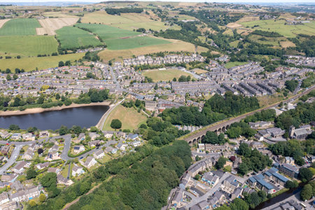 Aerial photo of the historic Yorkshire town of Huddersfield in the UK, showing the residential housing estates by a lake and train viaduct on a sunny day in the summer timeの写真素材