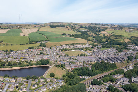 Aerial photo of the historic Yorkshire town of Huddersfield in the UK, showing the residential housing estates by a lake and train viaduct on a sunny day in the summer timeの写真素材