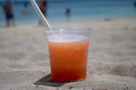 Close up of a orange and mango tropical cocktail on a beautiful tropical sandy beach.の写真素材