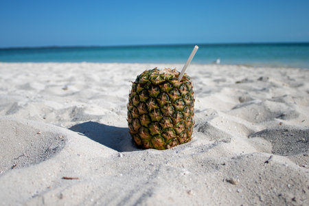 Close up of a pineapple cocktail drink on a beautiful exotic tropical sandy beachの写真素材