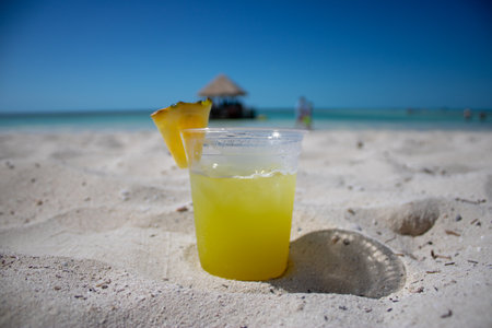 Close up of a tropical cocktail drink on a beautiful tropical sandy beach.