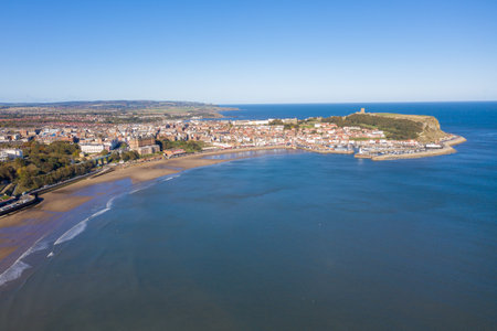 Aerial photo of the British seaside town of Scarborough, the seaside coastal town is located in East Yorkshire in the North Sea coast showing the sandy beach front, ocean and boats in the harbourの写真素材