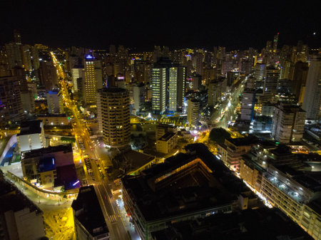 Night time aerial photo of the town of Benidorm in Spain and the beach known as Playa Levante beach showing hotels, buildings, restaurants and the coastline front.の写真素材