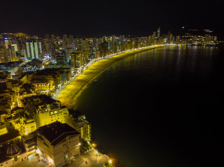 Night time aerial photo of the town of Benidorm in Spain and the beach known as Playa Levante beach showing hotels, buildings, restaurants and the coastline front.の写真素材