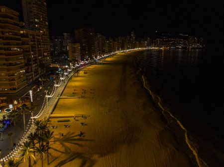 Night time aerial photo of the town of Benidorm in Spain and the beach known as Playa Levante beach showing hotels, buildings, restaurants and the coastline front.の写真素材