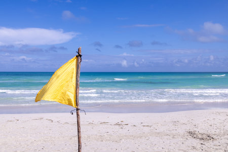 The beautiful beach front of the Cuban beach at Varadero showing a yellow flag on a stick with the...