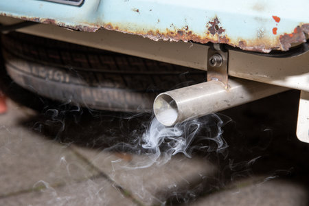 A smoking exhaust tail pipe from an old rusty car showing the smoky emotions coming from the cars engineの写真素材