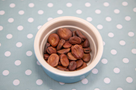 A bowl of broad beans on a kitchen table ready to be cooked in a dish