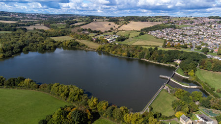 Aerial drone photo of the large Worsbrough reservoir in the village of Worsbrough, Barnsley in Sheffield in the UK, showing the British village and housing estates in the summer timeの写真素材