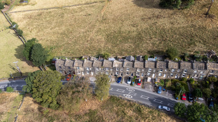 Aerial drone photo of the beautiful village of East Morton in Keighley in Yorkshire in the UK, showing old historic rows of traditional terraced houses by a road surrounded by farmers fields.の写真素材