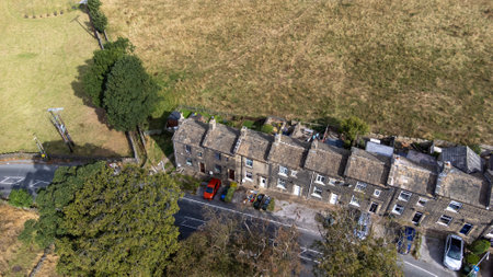 Aerial drone photo of the beautiful village of East Morton in Keighley in Yorkshire in the UK, showing old historic rows of traditional terraced houses by a road surrounded by farmers fields.の写真素材