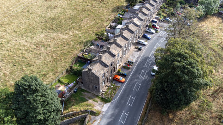 Aerial drone photo of the beautiful village of East Morton in Keighley in Yorkshire in the UK, showing old historic rows of traditional terraced houses by a road surrounded by farmers fields.の写真素材