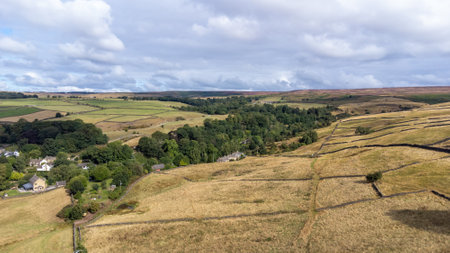 Aerial drone photo of the beautiful village of East Morton in Keighley in Yorkshire in the UK, showing old historic rows of traditional terraced houses by a road surrounded by farmers fields.の写真素材