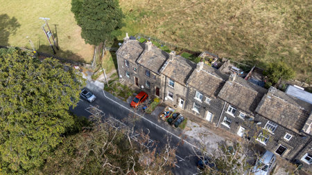 Aerial drone photo of the beautiful village of East Morton in Keighley in Yorkshire in the UK, showing old historic rows of traditional terraced houses by a road surrounded by farmers fields.の写真素材