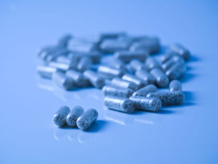 Blue tinted picture of  pills on reflective surface and with selective focusの写真素材