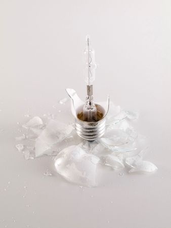 Macro of  a broken light bulb on reflective white surface