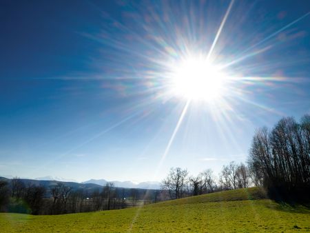 Meadow under spring sun with mountains on the backgroundの写真素材