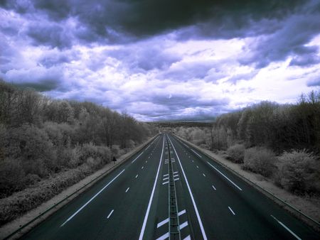 Infrared picture of an empty highway with stormy clouds