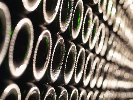 Row of Bordeaux wine bottles stacked in a cellar with shallow depth of field