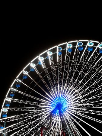 Rotating Ferris wheel at night with blue and red colorsの写真素材