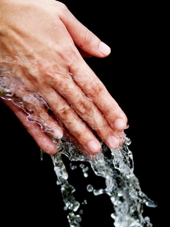 Young woman cleaning her hand with pure water on black background
