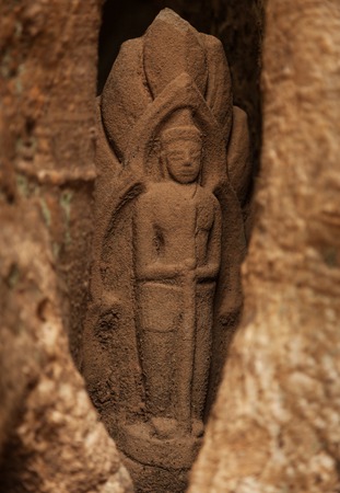 Small hidden sandstone statue in Angkor temple inside a treeの写真素材
