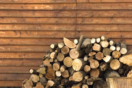 dry  pile of logs stacked near house wall.