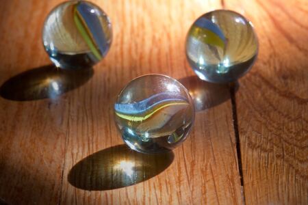 Colorful marbles on a wooden floor lit by the morning sunの写真素材