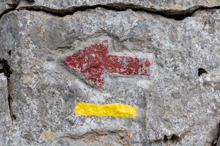 Close-up of a red and yellow arrow on a stone wallの写真素材