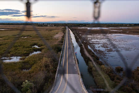 Aerial view of a highway through the marshlands during sunset.の写真素材