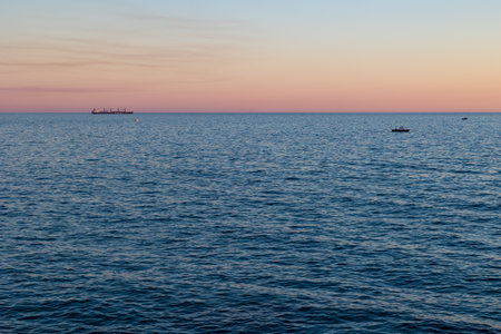 View of the Mediterranean Sea from the mÃ´le de SÃ¨te at sunset with a bulk carrier and a small tourist boat (Occitanie, France)のeditorial素材