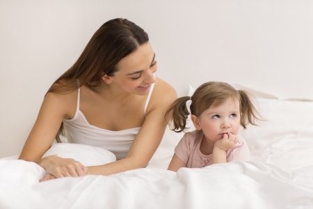 dispute between a child and her mom in white bedroomの写真素材