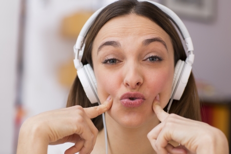 Attractive girl enjoying music through headphones, on sofaの写真素材