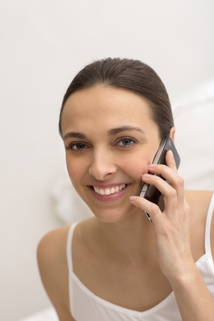 Young girl using  black smart phone on bedの写真素材